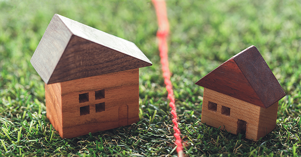 Boundary Dispute from Parachute Law: Two children's wood block toy houses sit on false grass, separated by a line of red string.