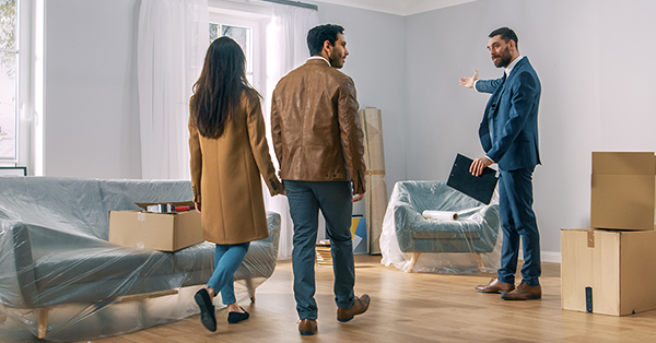 Estate Agents' Legal Obligations to Buyers & What to do if they are not met. A guide from Parachute Law. An estate agent in a blue suit shows a young couple around a light airy property.