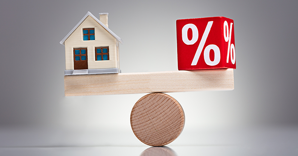 Beneficial Interest in Property from Parachute Law: a model house and a square block which reads '%' sit atop a long children's playing block, in balance on a cylindrical block Beneficial Interest in Property from Parachute Law: a model house and a square block which reads '%' sit atop a long children's playing block, in balance on a cylindrical block