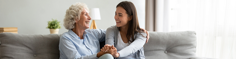 Mother and daughter sitting on the sofa in their new home. Parachute Law's guide to buying a house jointly with parents