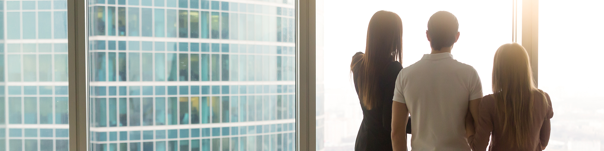 buying a property through a limited company from Parachute Law. A couple and a tall estate agent look out of a glass wall in a modern high rise apartment building