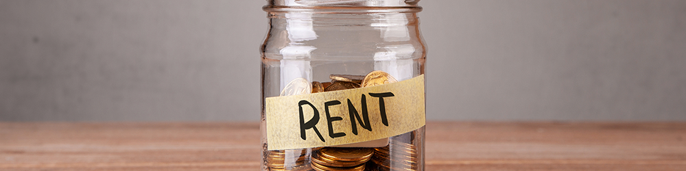 A hand places copper coins into a glass jar labelled 'Rent' - Occupational Rent: Can I charge rent to my ex? A Guide from Parachute Law
