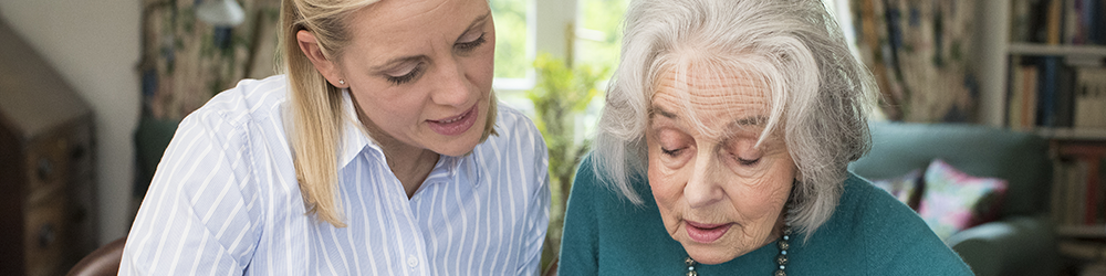 Power of Attorney for Property from Parachute Law: A young woman reads and explains a document to an elderly woman at a desk